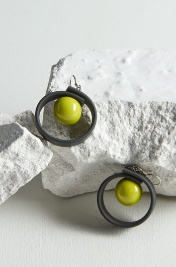 A pair of Tempo Earrings, crafted through jewellery making on a rock.