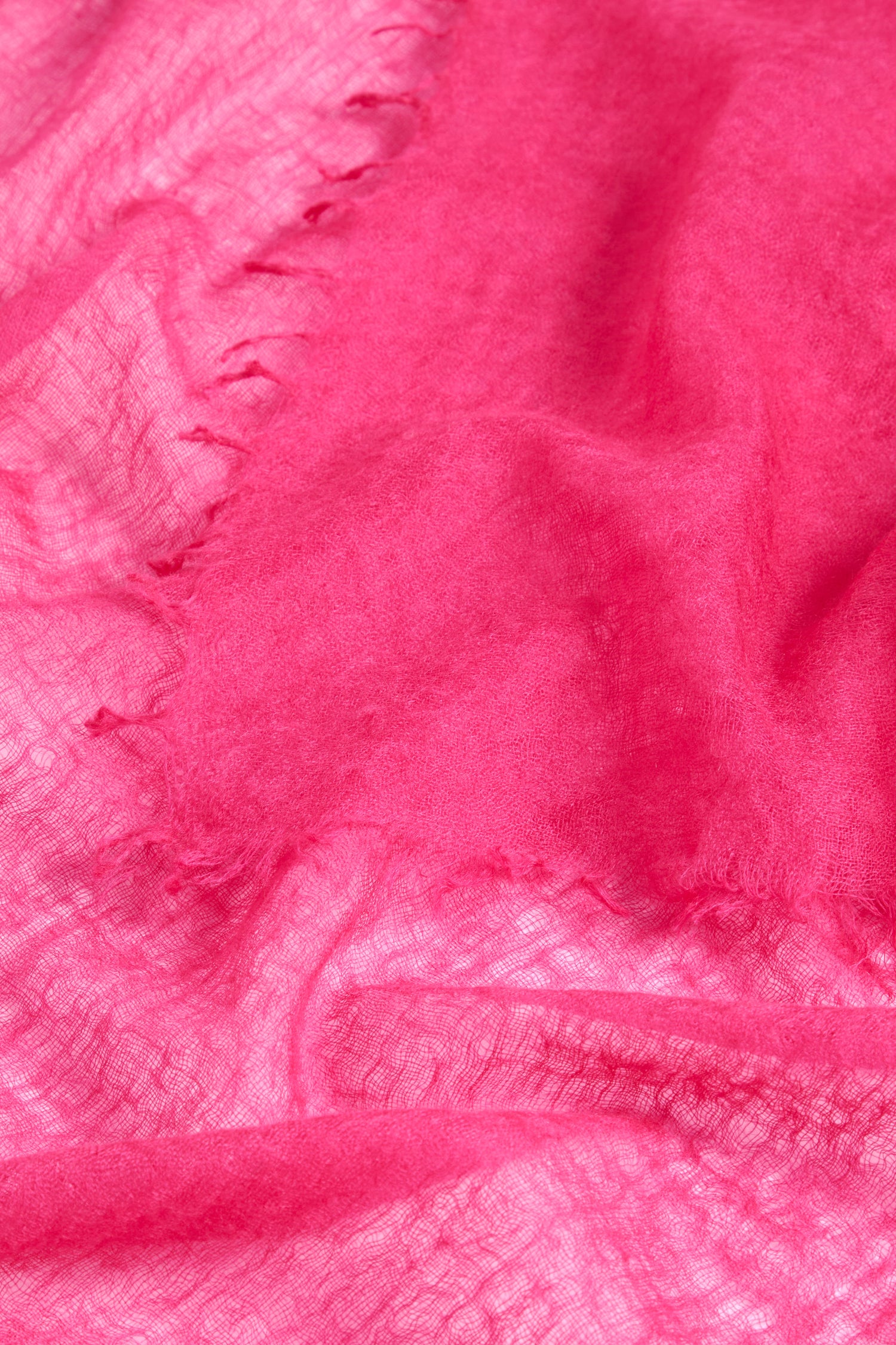 A Soft Weave Cashmere Scarf in pink, featuring a crumpled, semi-transparent fabric with a slightly worn texture and visible frayed edges, resembling a raw-edge tassel finish.