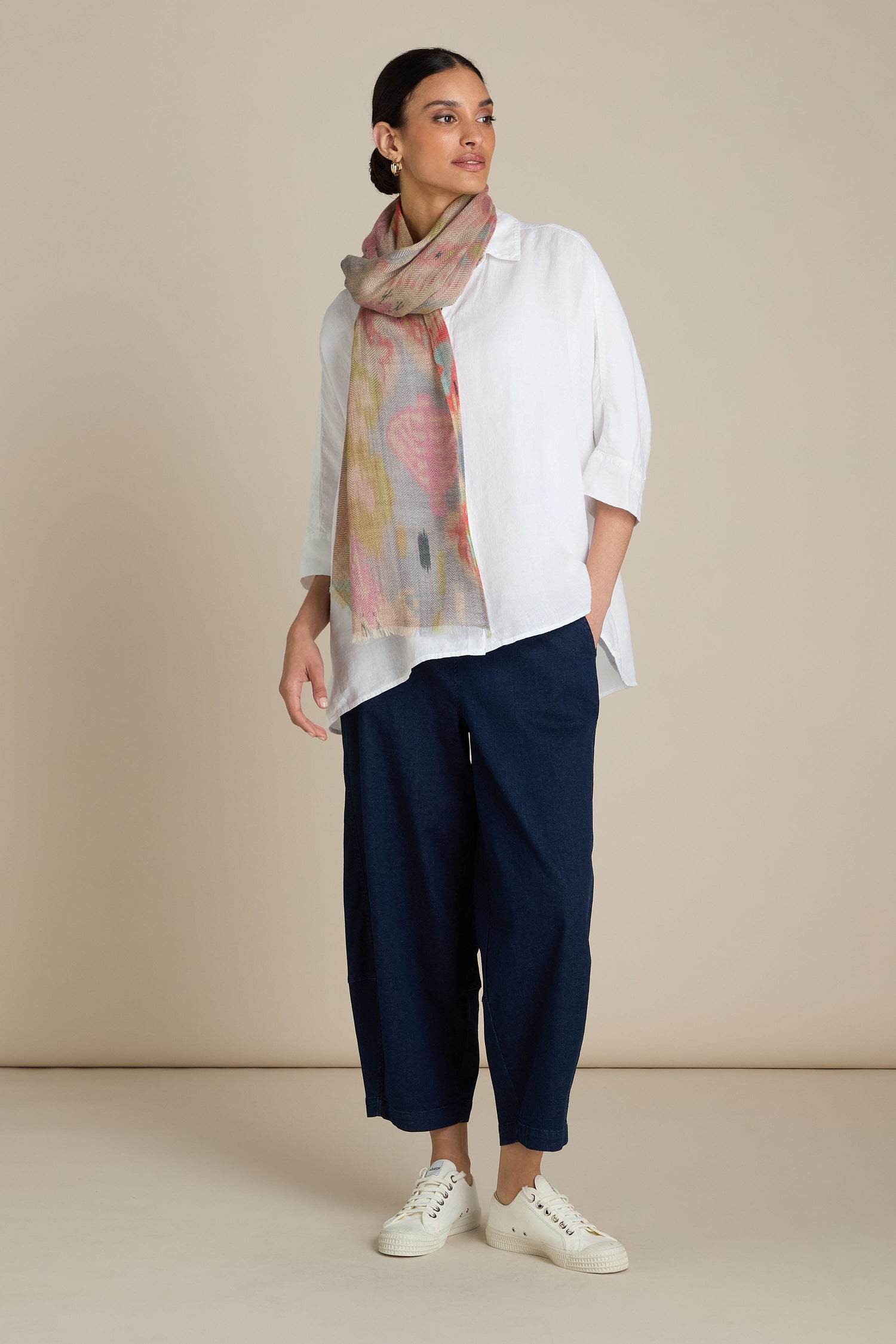 A person stands against a plain background wearing a white blouse, blue wide-leg pants, white sneakers, and the Decorative Wool Cashmere Blend Scarf that adds a touch of sophistication.