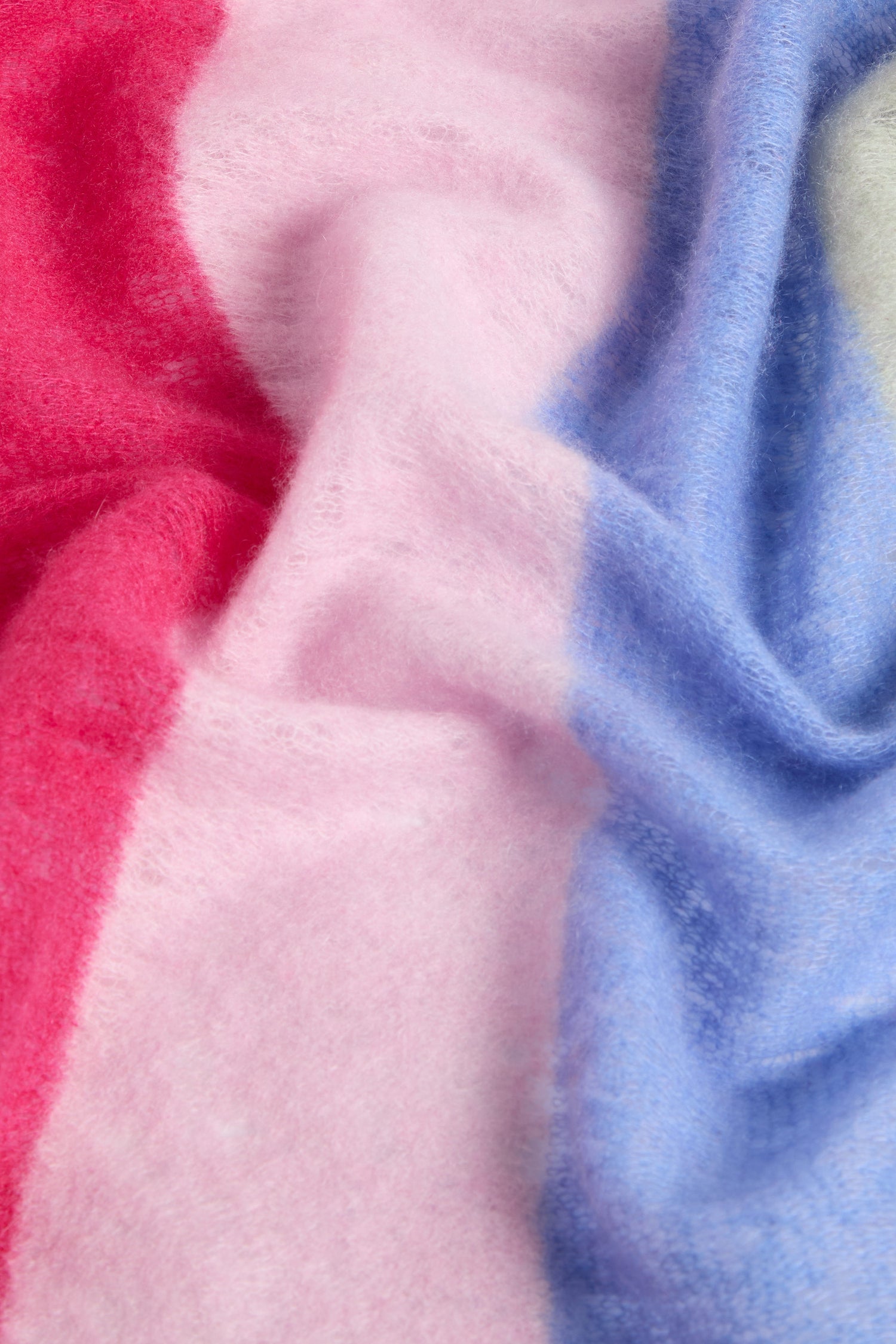 A detailed view of the Rainbow Stripe Cashmere Scarf showcases its vibrant, soft, and plush fabric adorned with red, pink, and blue sections—ideal for creating an elegant striped scarf that exudes an Autumn aesthetic with its rich colors and pure 100% Cashmere quality.