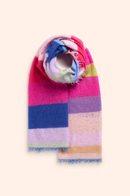 The Rainbow Stripe Cashmere Scarf, featuring vibrant horizontal stripes in pink, blue, green, and purple tones, is folded and laid flat on a light beige surface. Perfect for an Autumn look and crafted from 100% Cashmere for ultimate softness and warmth.