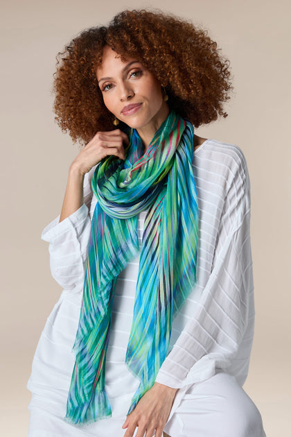 A woman wearing a vibrant blue and green Ikat Zig Zag Scarf.