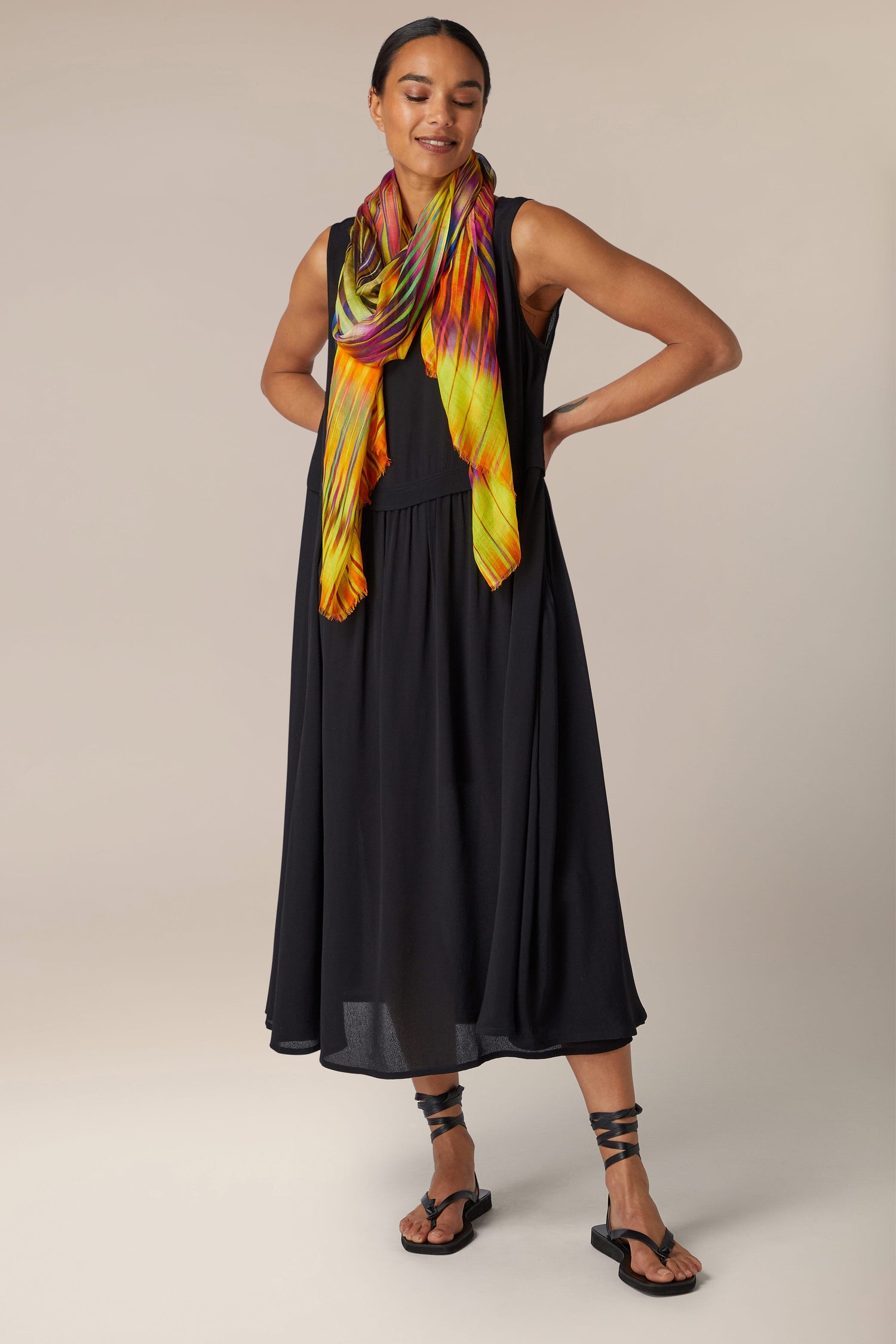 A woman wearing a black dress and an Ikat Zig Zag Scarf in vibrant blues and greens.