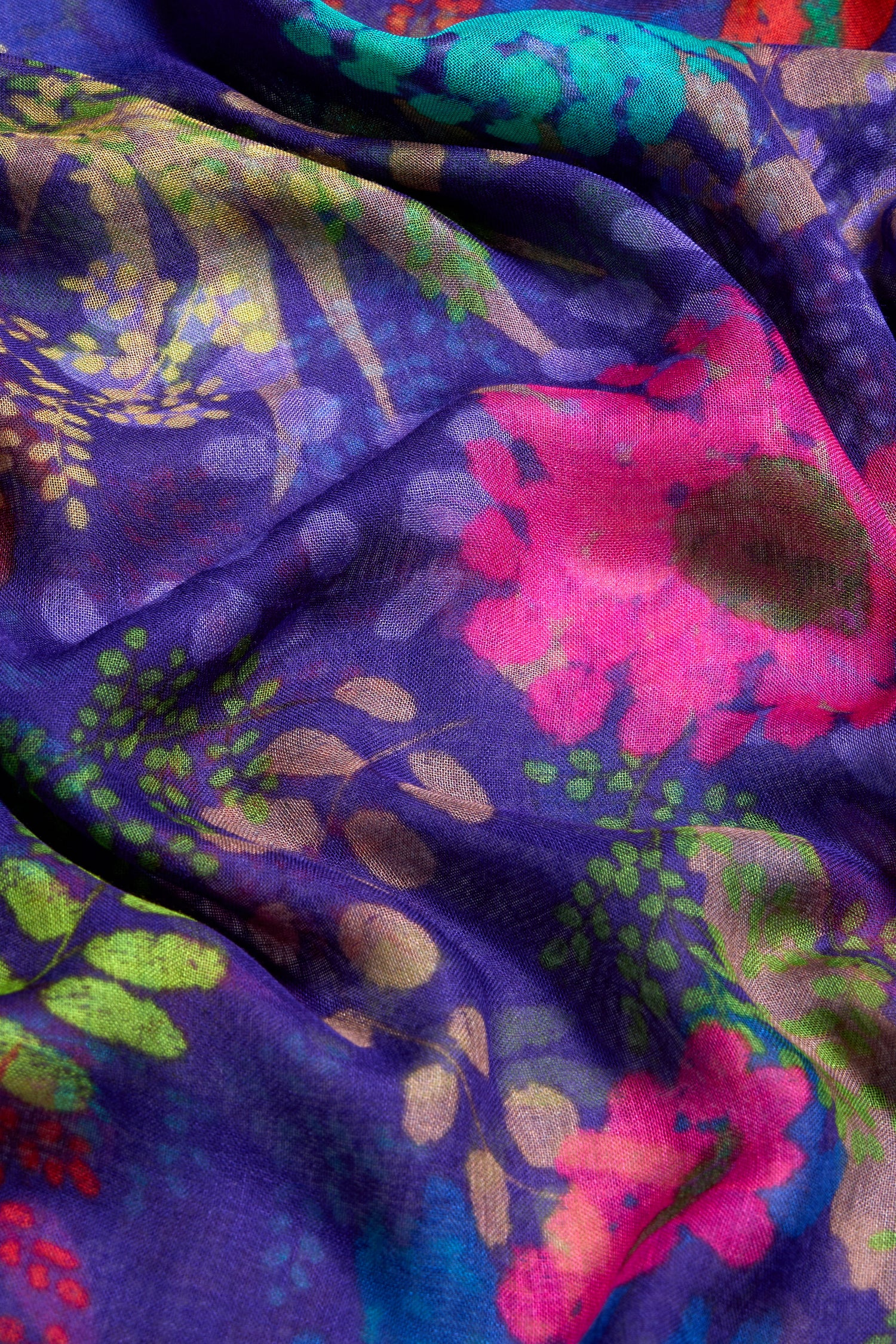 Close-up of the Bright Blooming Garden Scarf, featuring a vibrant multicolored floral design on a purple background with visible folds, crafted from lightweight silk modal fabric.
