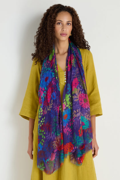 A woman wearing a yellow dress styles the Bright Blooming Garden Scarf, standing against a plain light background.