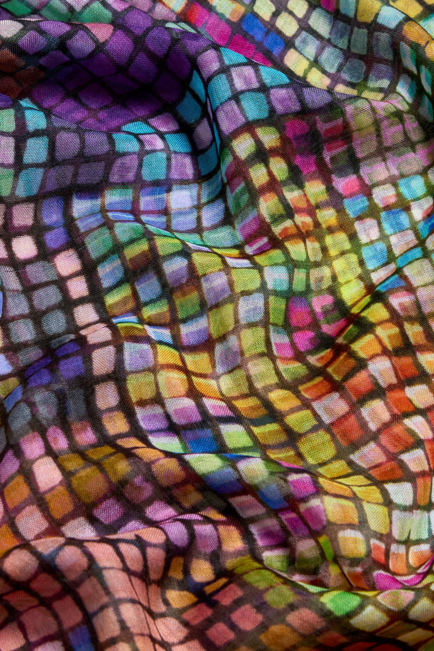A close-up of the Coloured Glass Tiles Scarf, showcasing its mosaic-inspired print with a grid of small, multicolored squares and visible folds and shadows.
