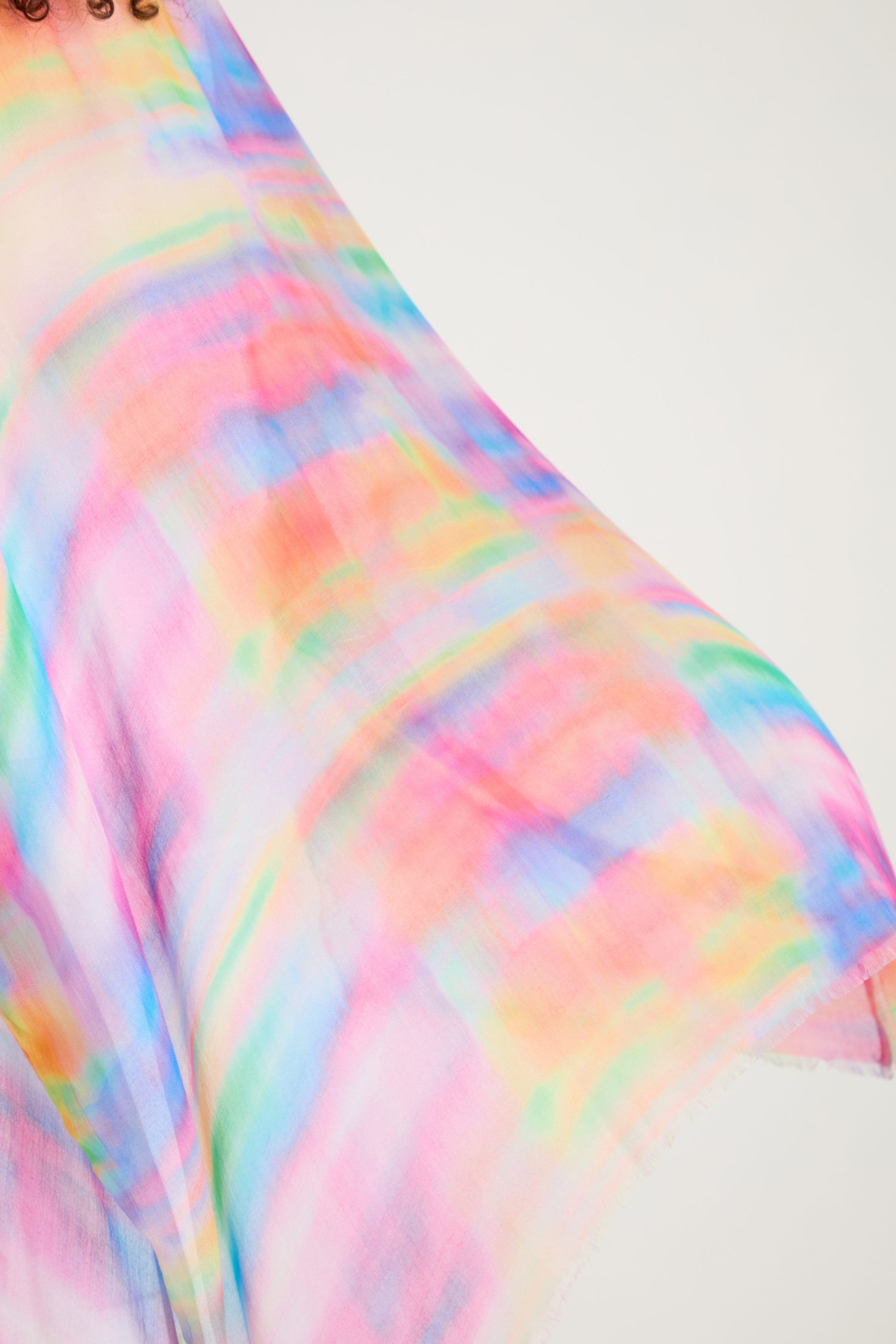 A close-up of the Painted Horizon Kimono, featuring a flowing, semi-sheer fabric with a watercolor-inspired multicolored pattern in pink, blue, green, yellow, and orange hues.