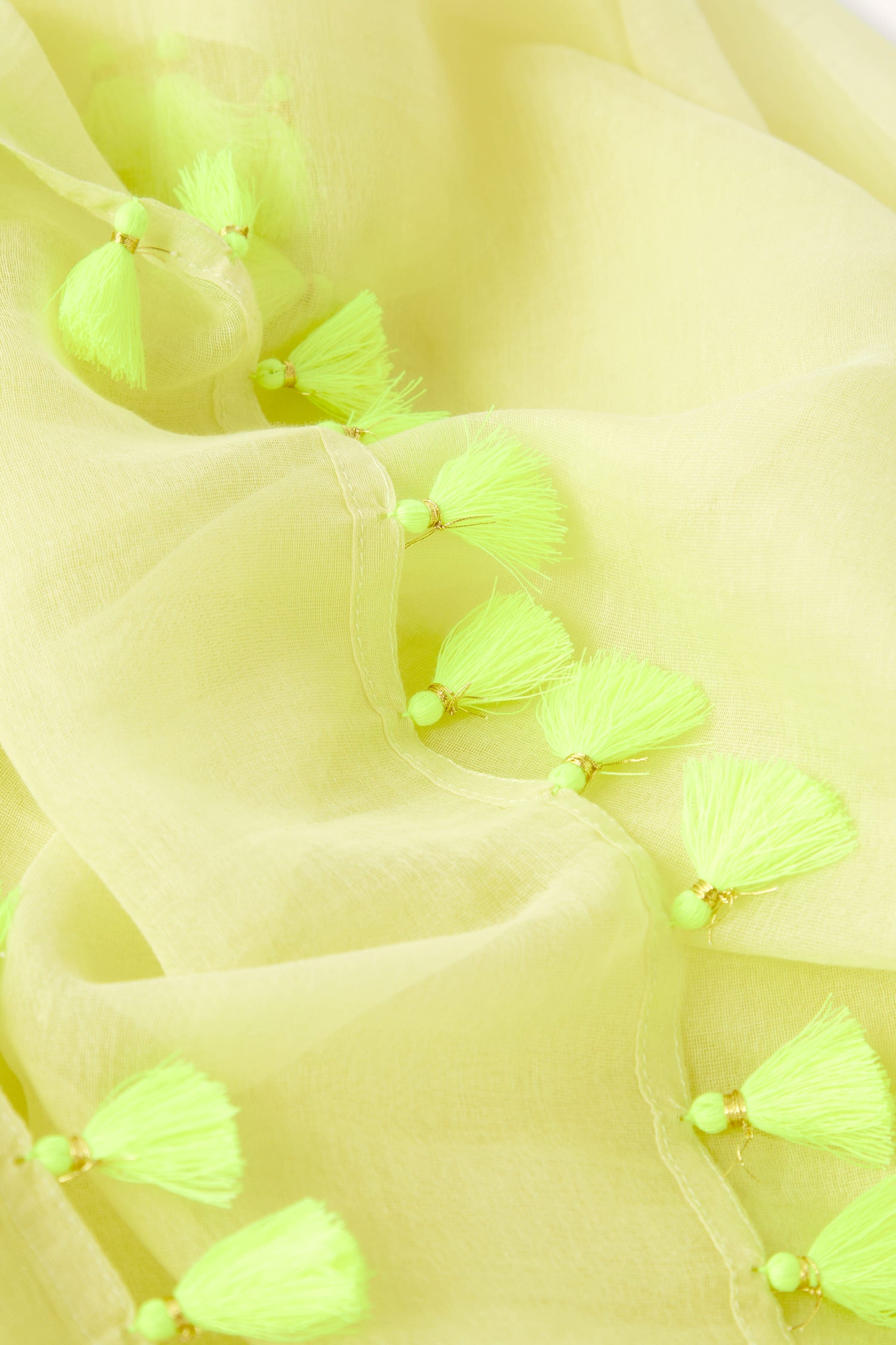 Close-up of a yellow fabric with Neon Tassel Scarf trim details.