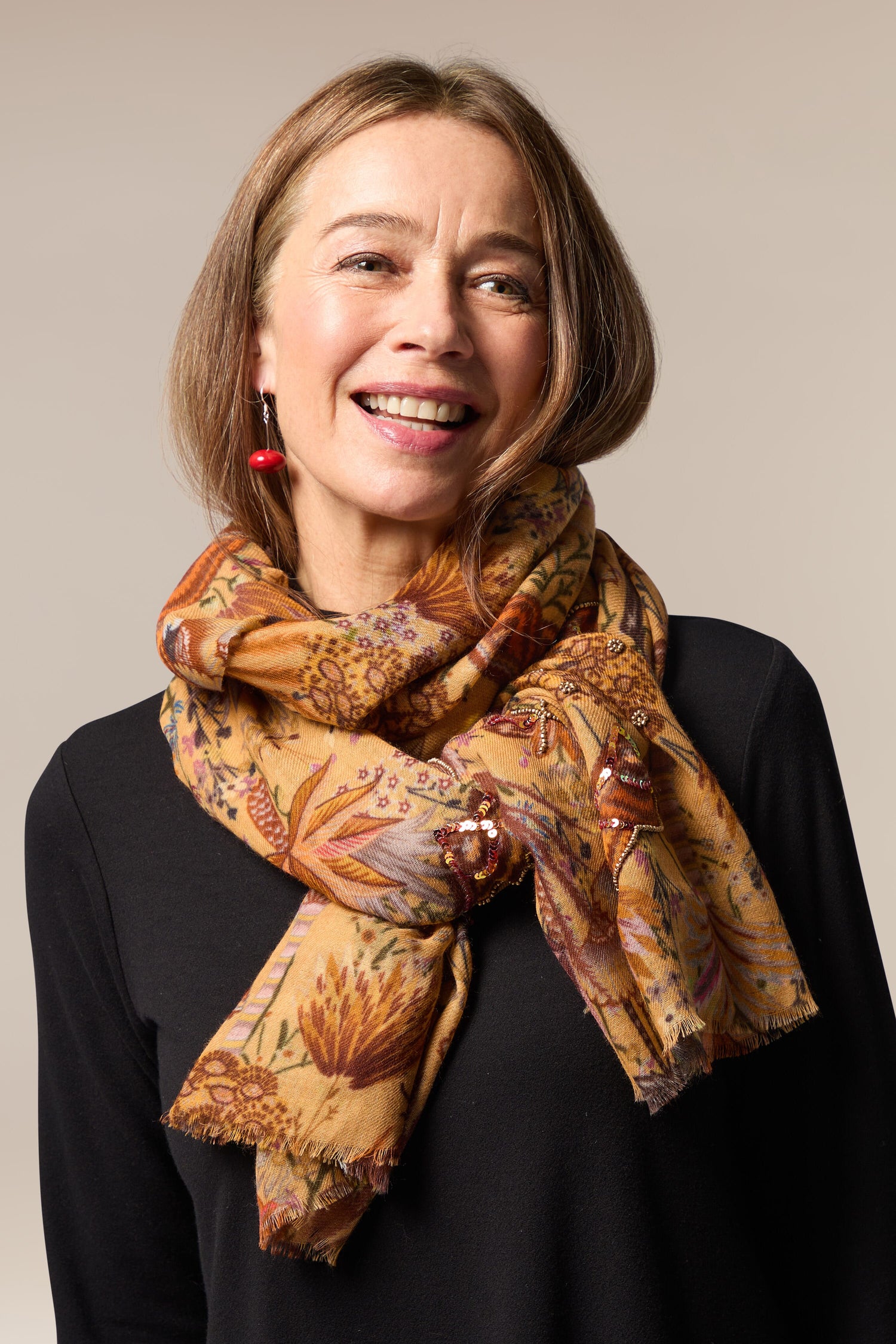 A woman wearing a Paradise Sequin Detail Wool Scarf with an intricate floral print.