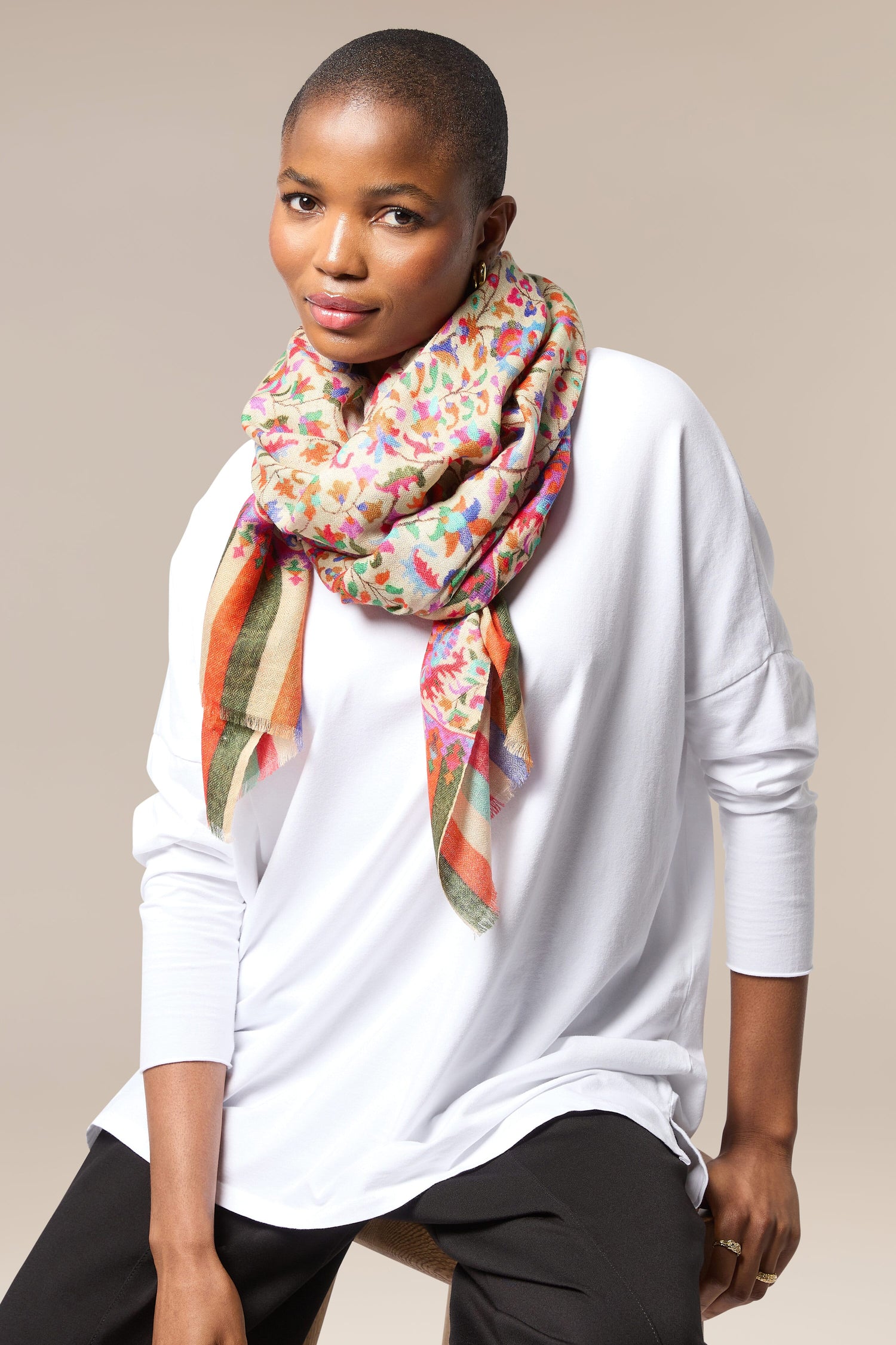 A woman in a white shirt and black pants wearing an Antique Floral Woollen Scarf, an accessory.