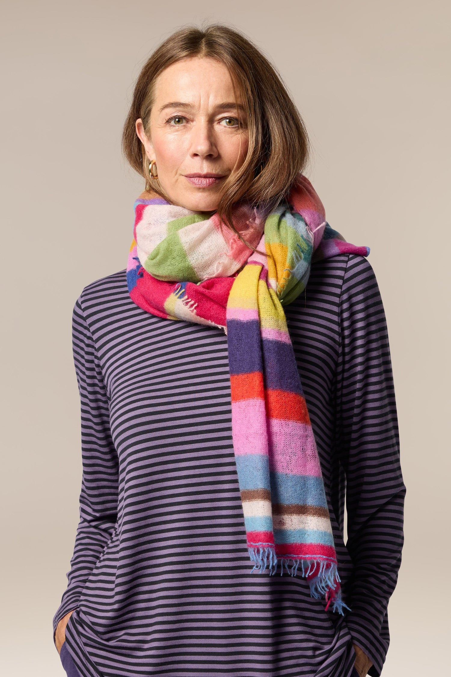 A woman wearing a Rainbow Stripe Cashmere Scarf.