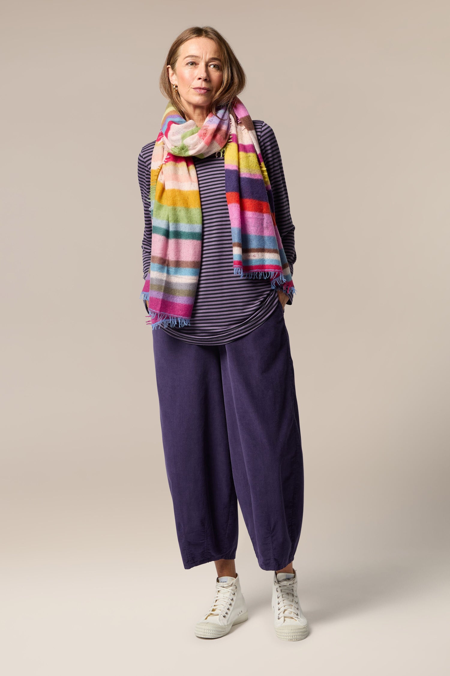 A woman wearing a Rainbow Stripe Cashmere Scarf.