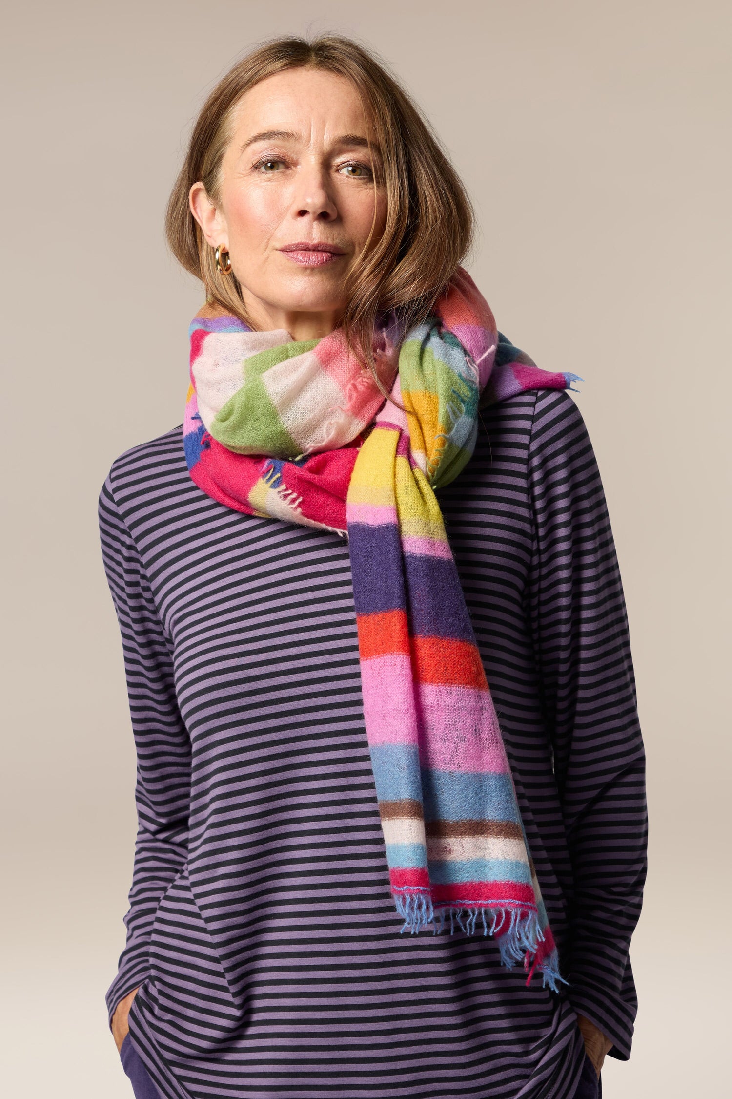 A woman wearing a Rainbow Stripe Cashmere Scarf, making it a statement accessory.