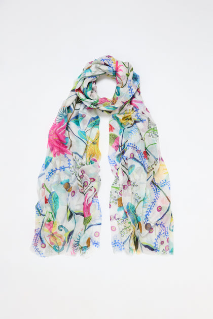 Introducing the Wild Garden Scarf, a lightweight accessory with a vibrant floral design featuring pink, yellow, and blue flowers with lush green leaves on a white background.