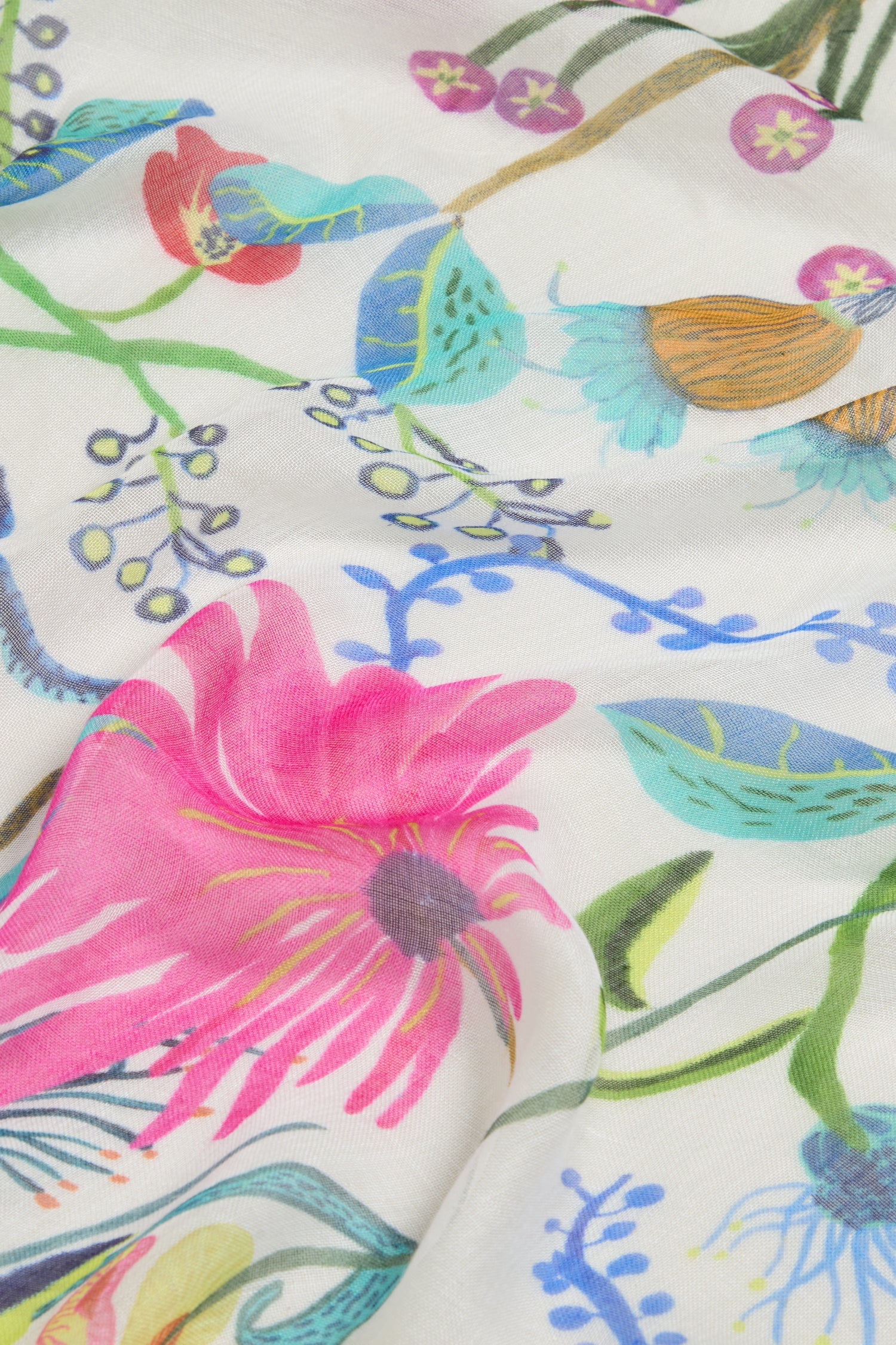 Close-up of the Wild Garden Scarf featuring a vibrant floral pattern with pink, blue, and green flowers on white. This lightweight scarf exudes elegance and charm.