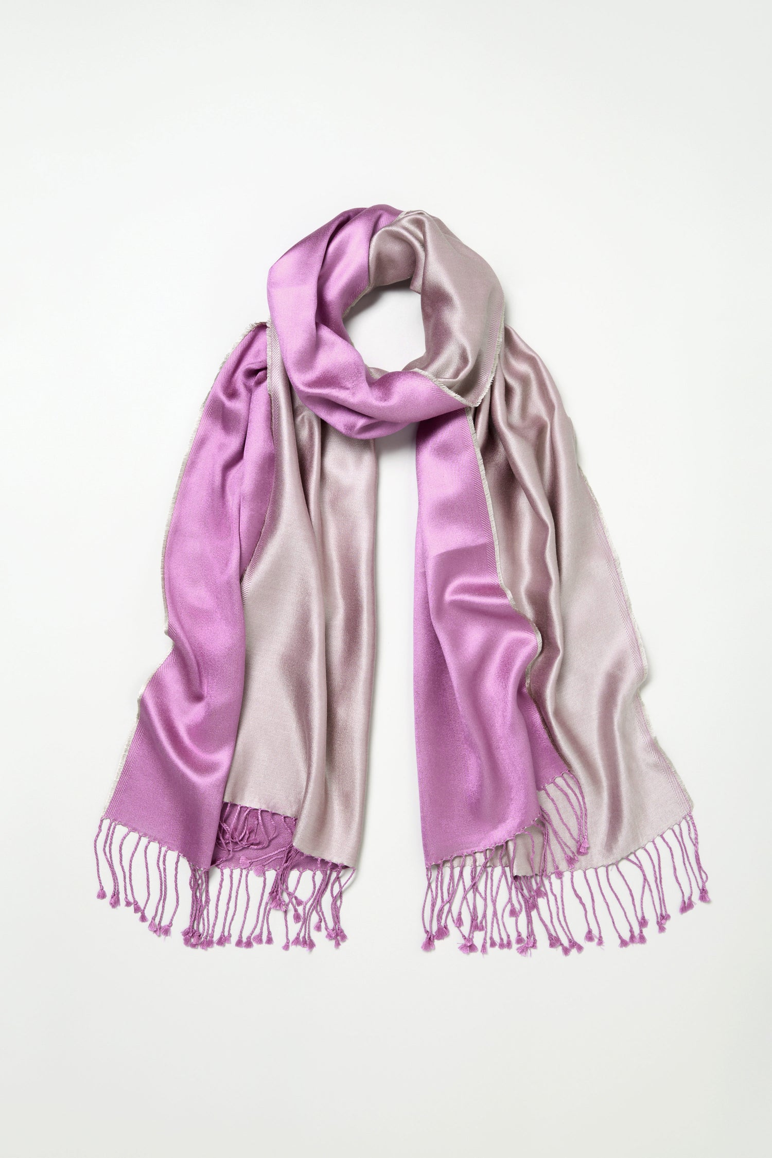 The Two Tone Silk Scarf, made of lustrous silk, showcases a colourblocked design in light purple and lavender with tasseled ends, and is displayed flat on a white background.