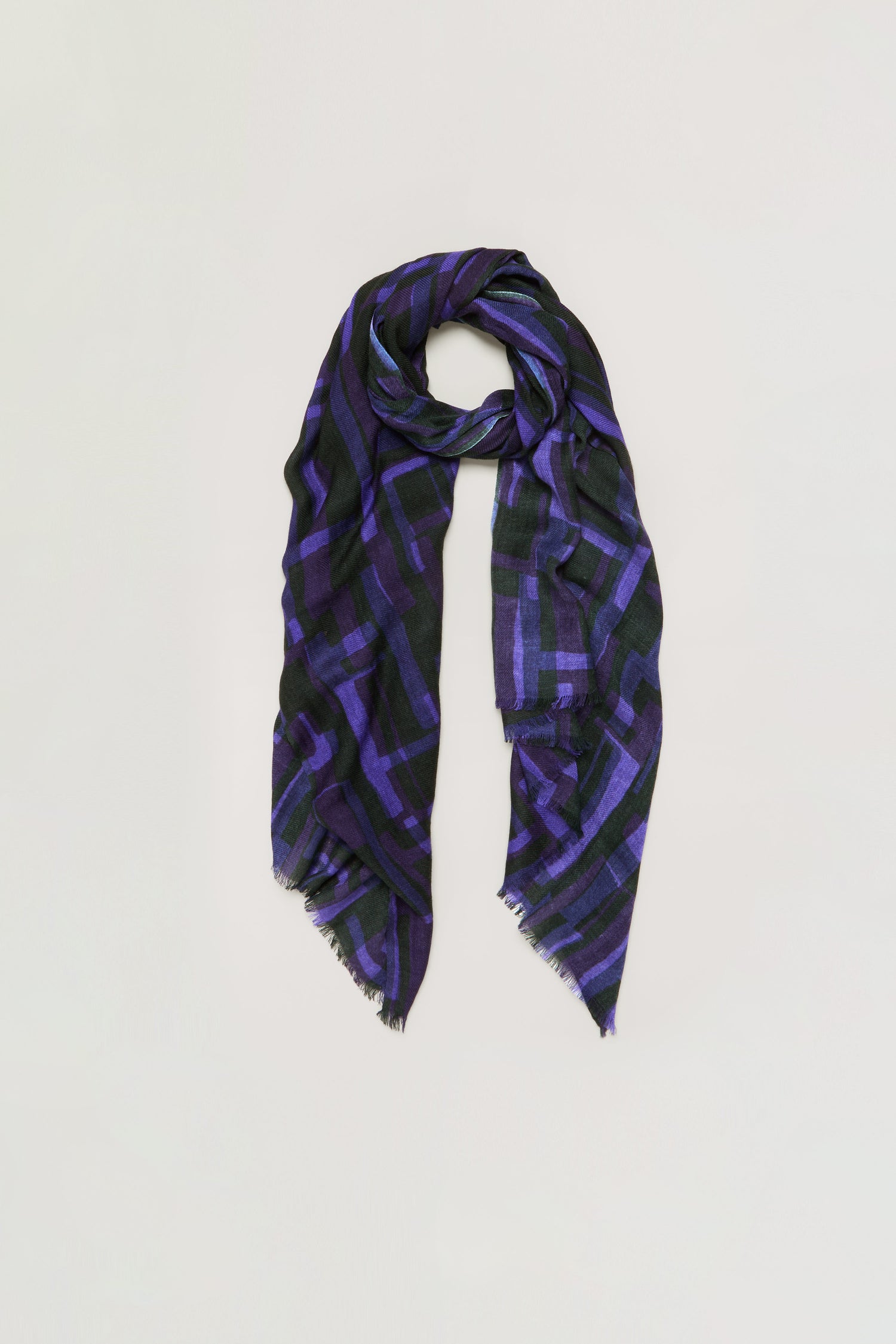 Layered Geometric Wool Scarf featuring a long rectangular shape with a black base, accented by a purple geometric pattern and subtly frayed edges, displayed against a plain light background.