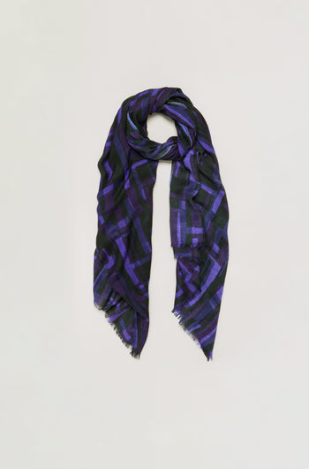 Layered Geometric Wool Scarf featuring a long rectangular shape with a black base, accented by a purple geometric pattern and subtly frayed edges, displayed against a plain light background.