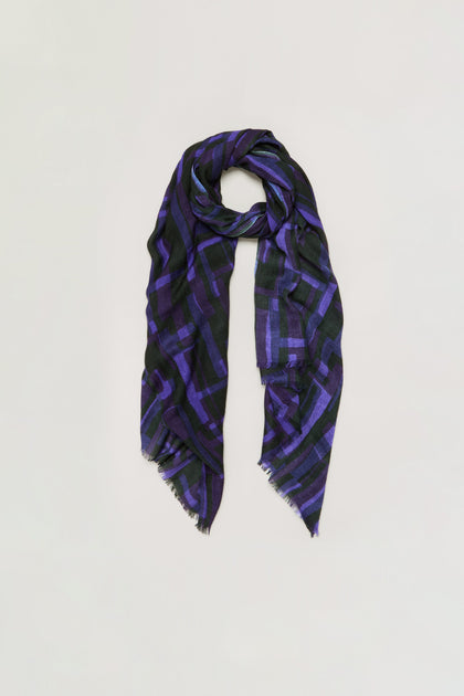 Layered Geometric Wool Scarf featuring a long rectangular shape with a black base, accented by a purple geometric pattern and subtly frayed edges, displayed against a plain light background.