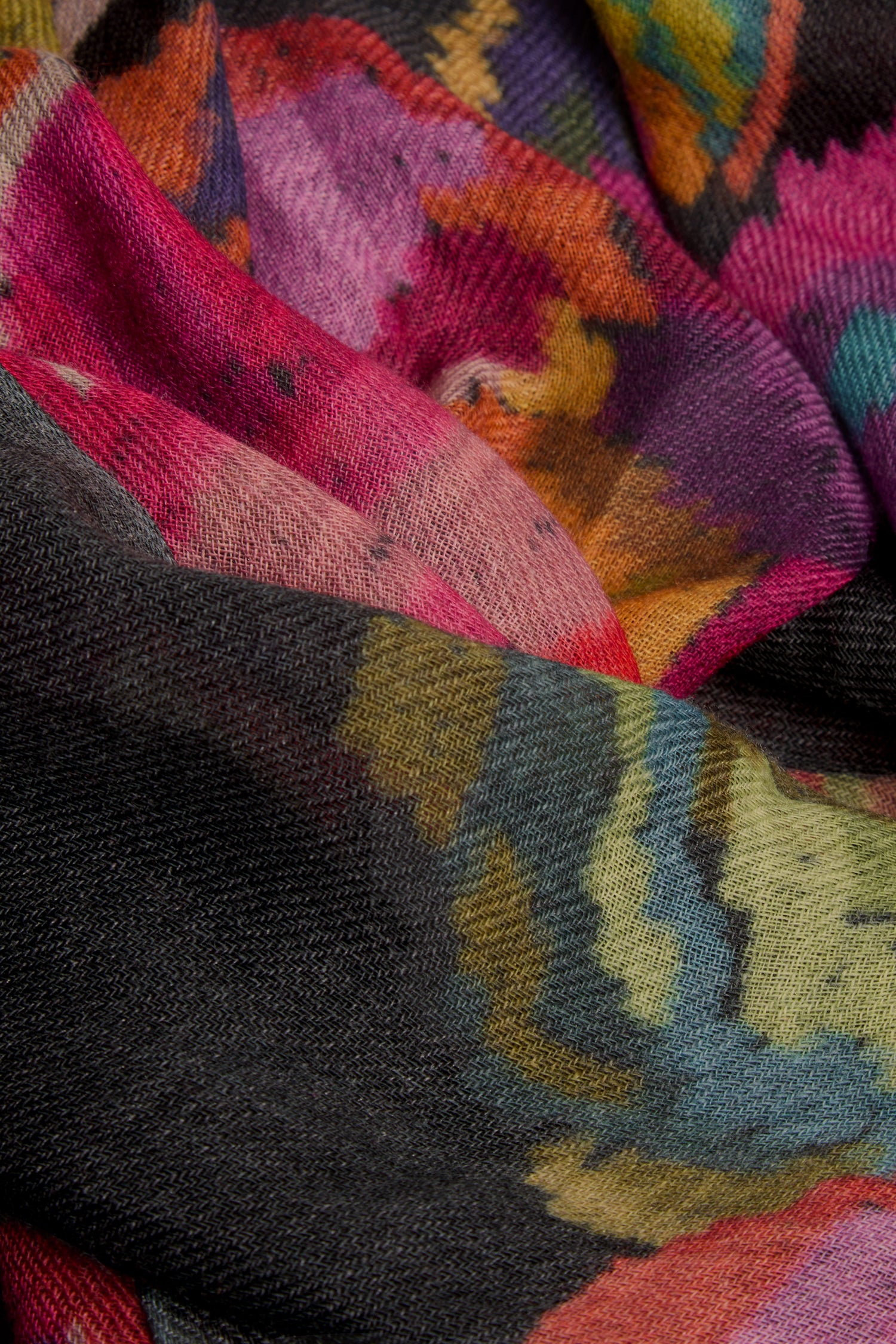 Close-up of the Pixelated Floral Wool Scarf showcasing its colorful, abstract botanical pattern in shades of pink, yellow, green, blue, and black with a clearly visible weave texture.