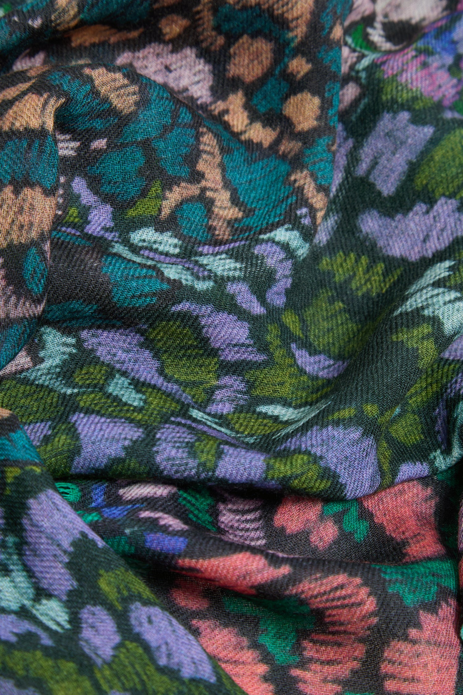 Close-up of the Winter Garden Wool Scarf, showcasing its textured wool fabric and multicolored floral design in green, purple, pink, and brown hues that evoke the elegance of a winter garden.