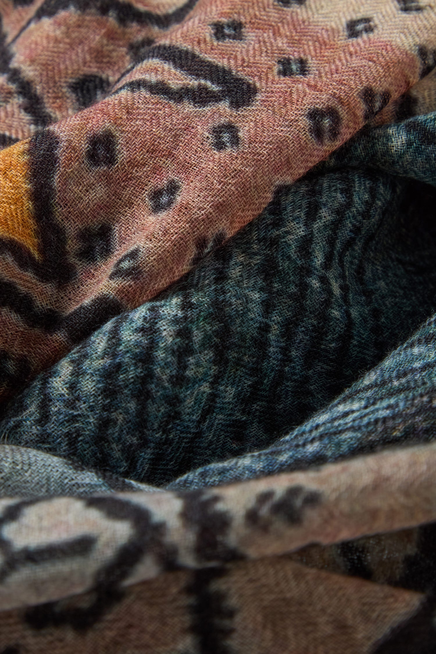 Close-up of the Sketch Mountain Wool Scarf, a lightweight accessory layered with abstract patterns in earthy tones—brown, orange, black, and blue—that highlight its varied textures and unique designs.
