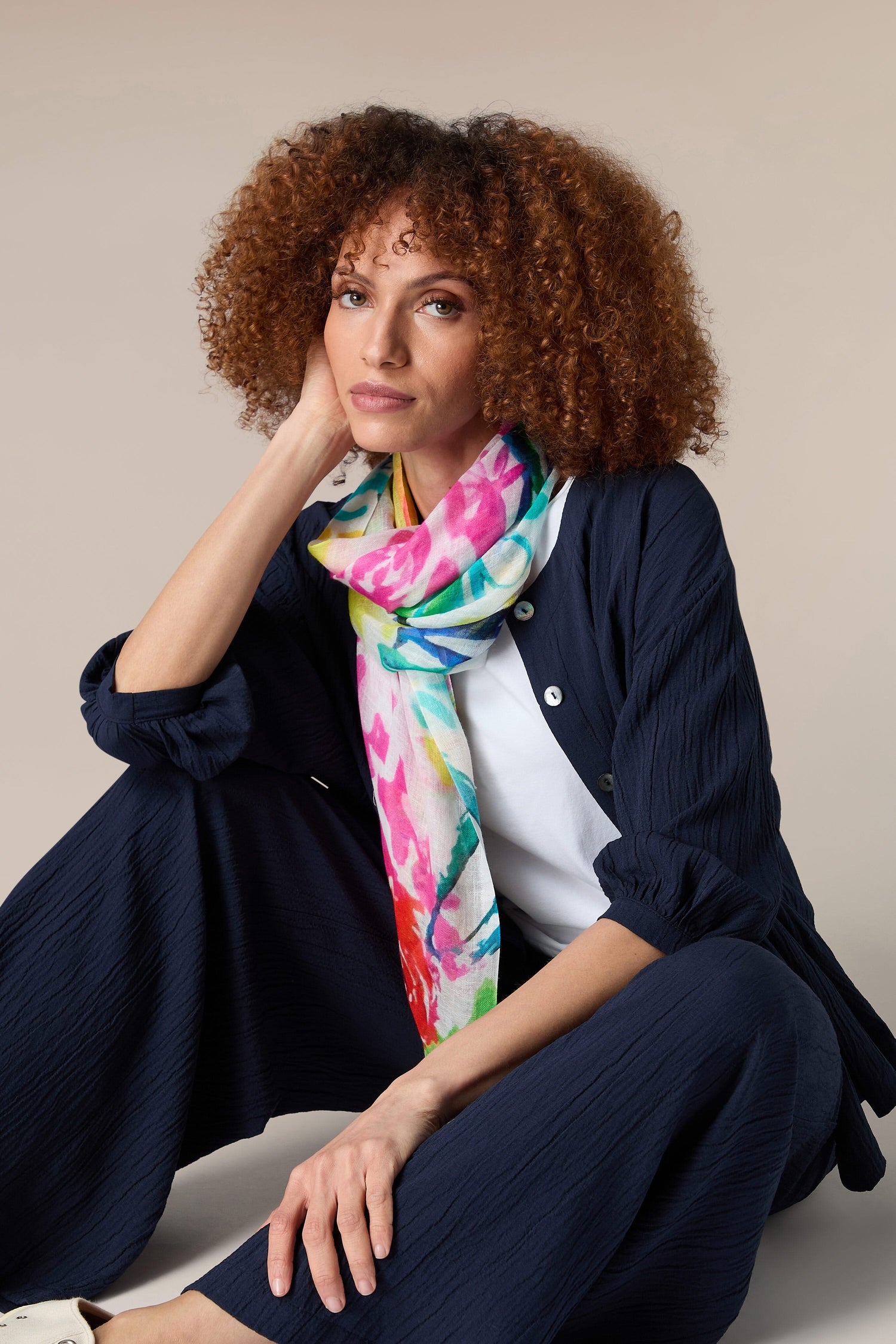 A woman with curly hair and a Graphic Floral Modal Scarf.