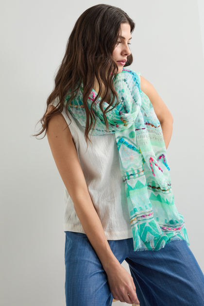 A person in a white sleeveless top and blue pants poses against a plain background, draping the Embroidered Zig Zag Stitch Scarf with intricate detailing over their shoulder.