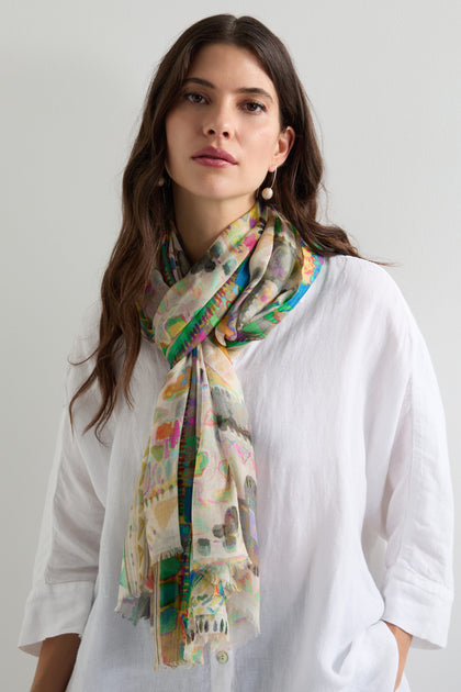 A person with long hair, dressed in a white shirt, wears a Collage Modal Scarf featuring an abstract print, standing against a plain background.