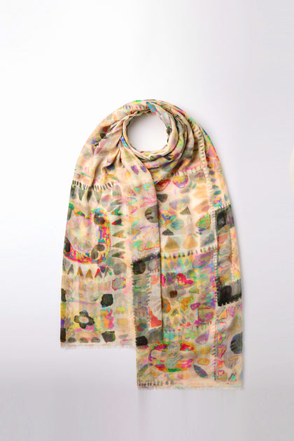 The Collage Modal Scarf, featuring a lively multicolored geometric pattern in yellow, green, blue, and pink hues, is elegantly displayed draped in a loop on a simple white background.