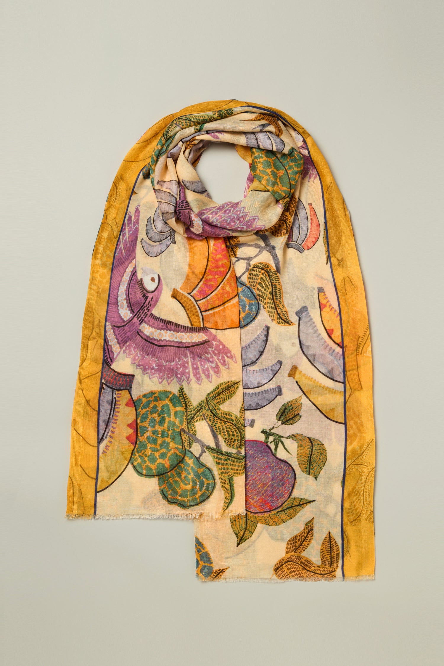 The Bird of Paradise Modal Scarf features a vibrant bird and floral pattern in yellow, purple, and green on a neutral backdrop. Made from ultra-soft modal fabric, it adds tropical flair to your wardrobe.