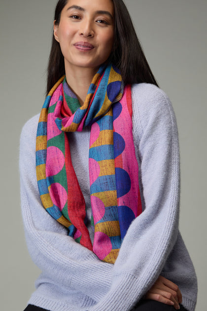 A woman in a light purple sweater and the Colour Pop Circles Wool Scarf, featuring large polka dots, poses against a plain background.