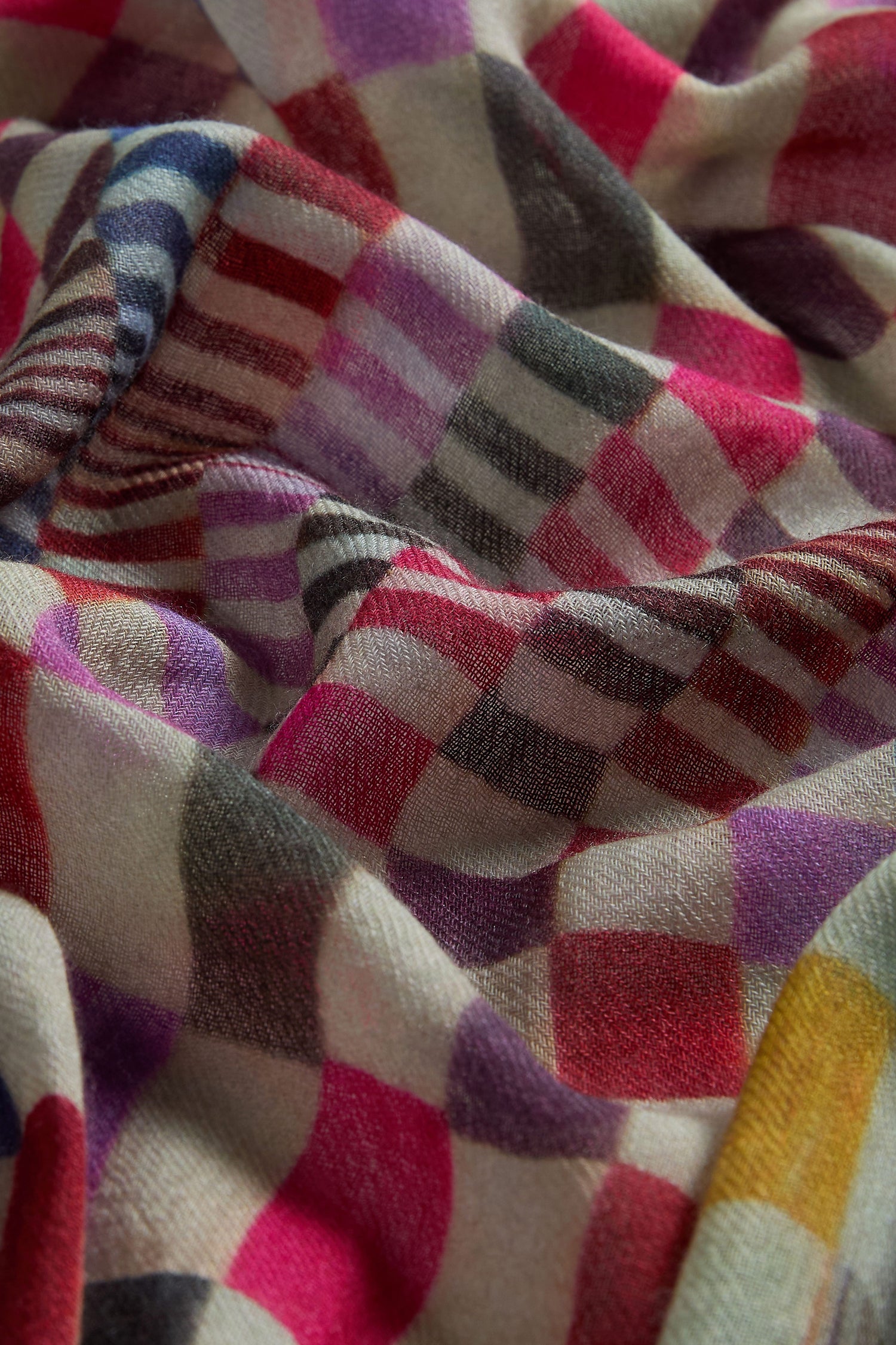 Close-up of the Mirage Check Wool Scarf, showcasing its soft texture and vibrant checkered pattern in red, purple, yellow, grey, and white.