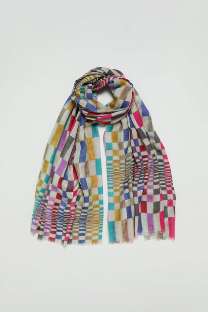 The Mirage Check Wool Scarf showcases a vibrant checkered pattern in red, blue, yellow, green, and beige hues, set against a plain white background.
