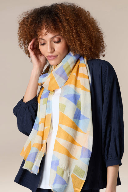 A woman wearing a bright Triangles Cotton Modal Scarf.