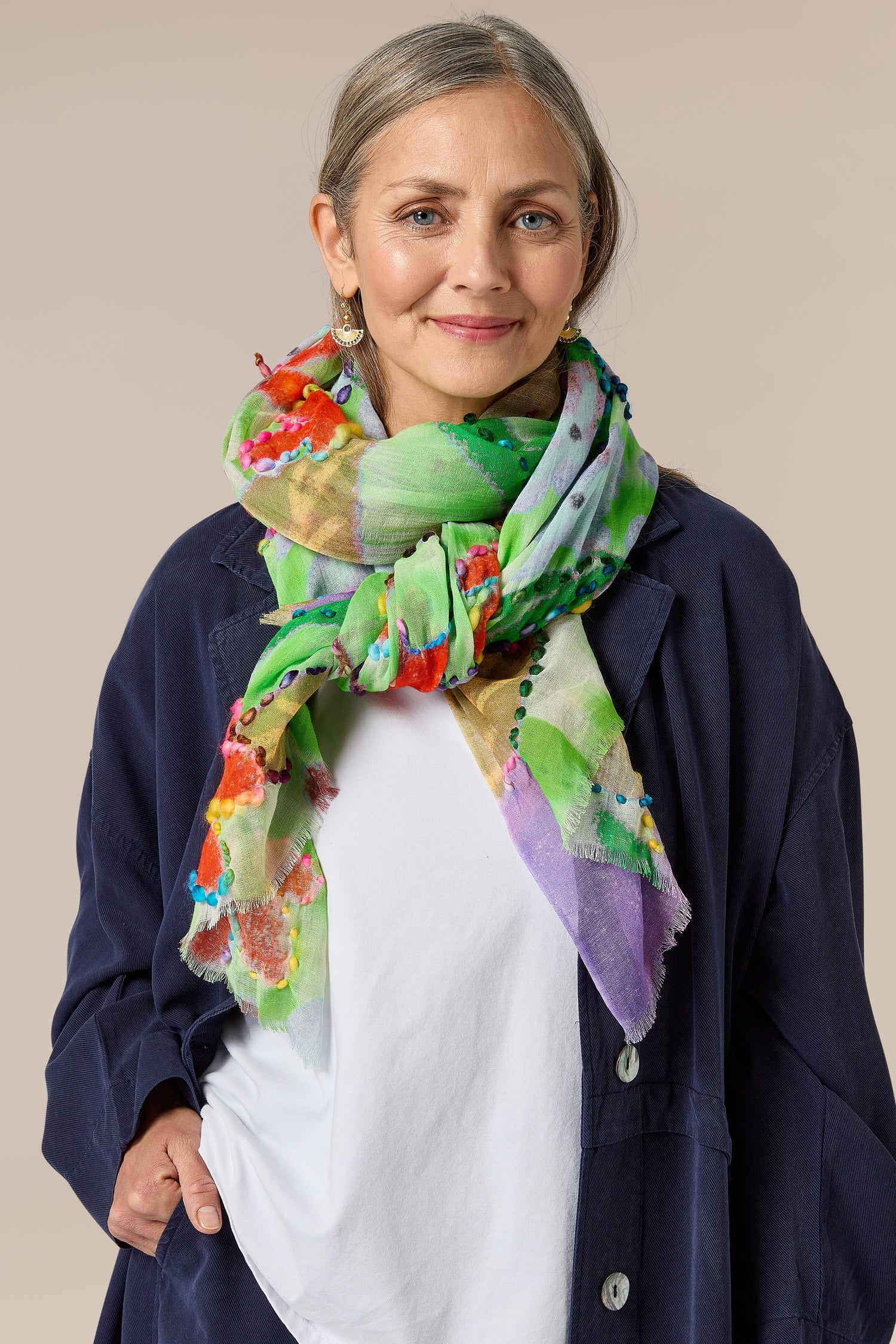 A woman wearing a Wild Garden Embroidered Scarf with an abstract floral pattern.