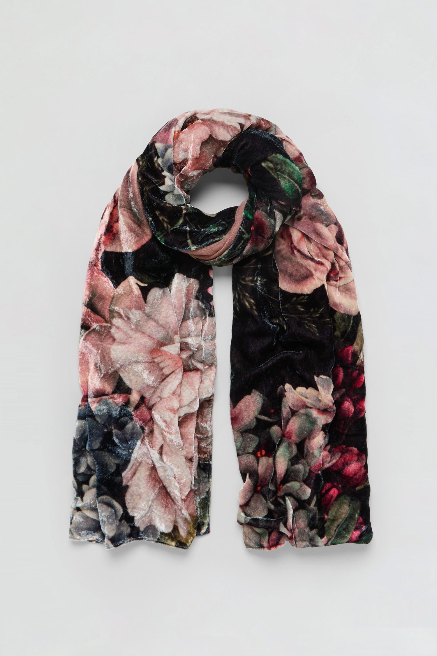 The Winter Rose Velvet Scarf, featuring a soft velvet fabric and a floral pattern in pink, green, and black hues, is displayed against a plain light background.