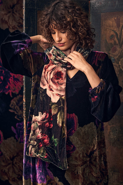 A person wearing a dark floral print Winter Rose Velvet Scarf draped around their neck.