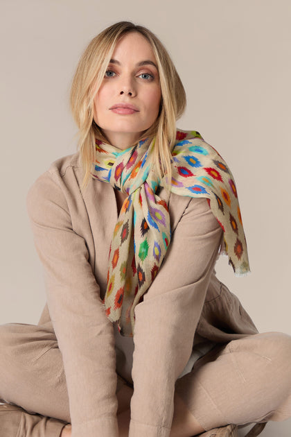 A woman is sitting on the floor wearing an elegant Geometric Diamond Modal Silk Scarf.