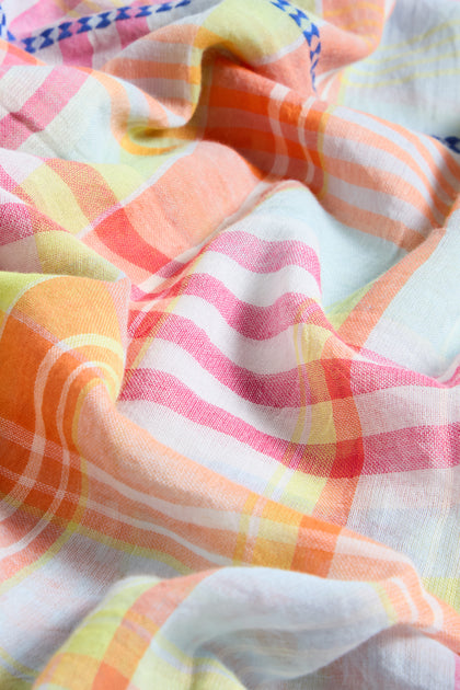 A close-up of the Blue Check Stitch Cotton Scarf, showcasing its wrinkled cotton fabric with a vibrant plaid pattern in orange, yellow, pink, and white, accented by a blue check stitch along the edge.