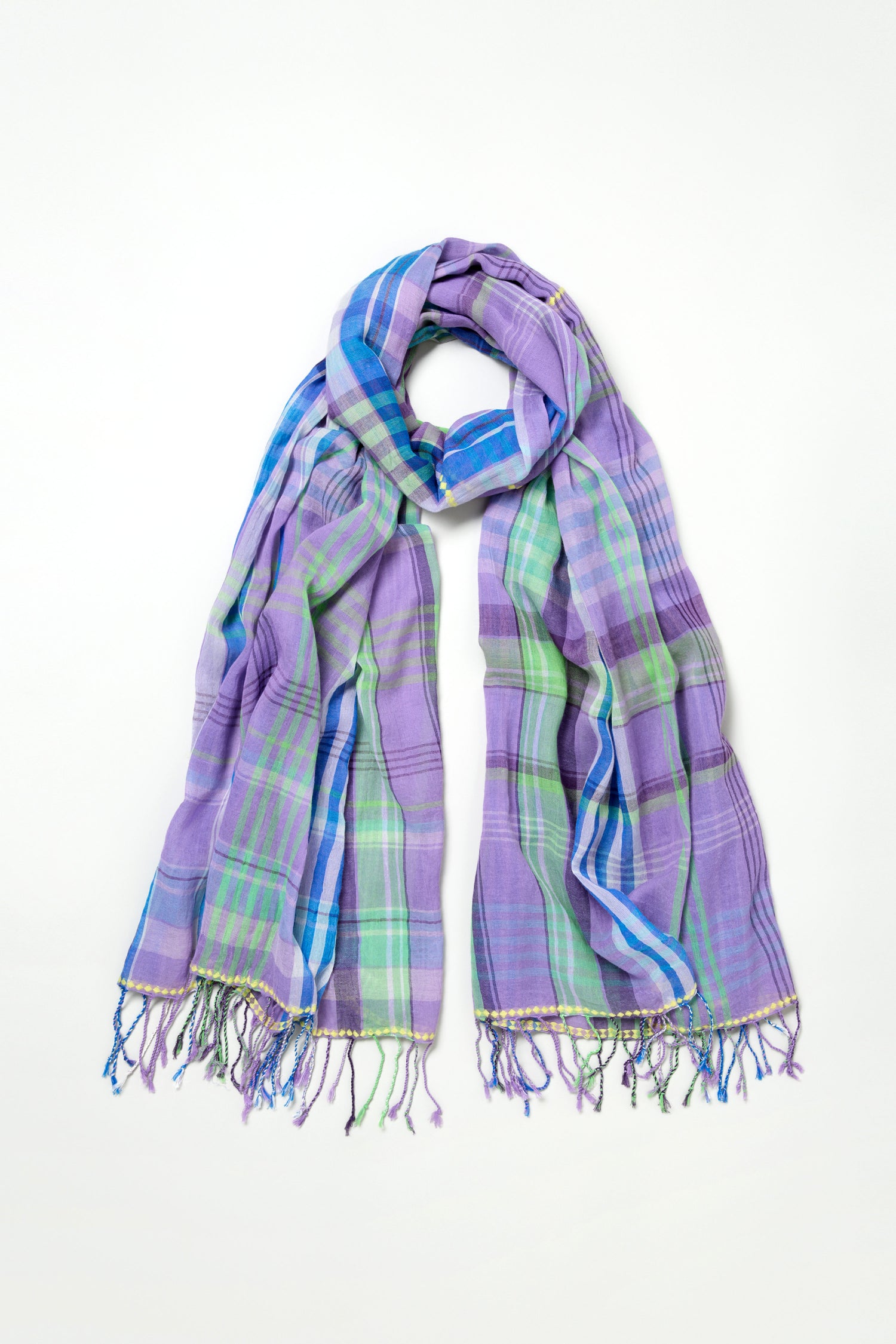 The Check Stitch Cotton Scarf is lightweight and breathable, featuring a purple, blue, and green plaid pattern with fringed ends and subtle check stitch accents, shown draped on a white background.
