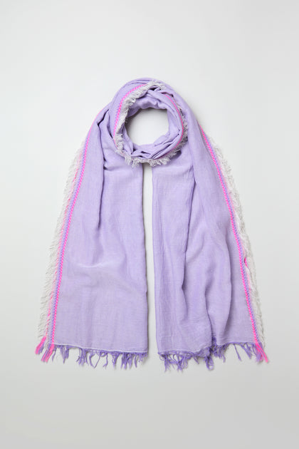 The Lilac Fringe Cotton Scarf, featuring a lightweight cotton fabric with white side fringe and pink accents, is laid flat on a plain light background.