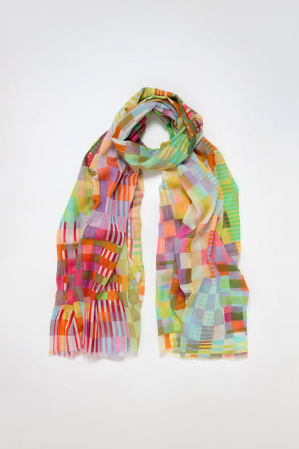 The Rainbow Checkerboard Cotton Modal Scarf showcases a vibrant checkered pattern with greens, blues, reds, and yellows on a solid white backdrop.