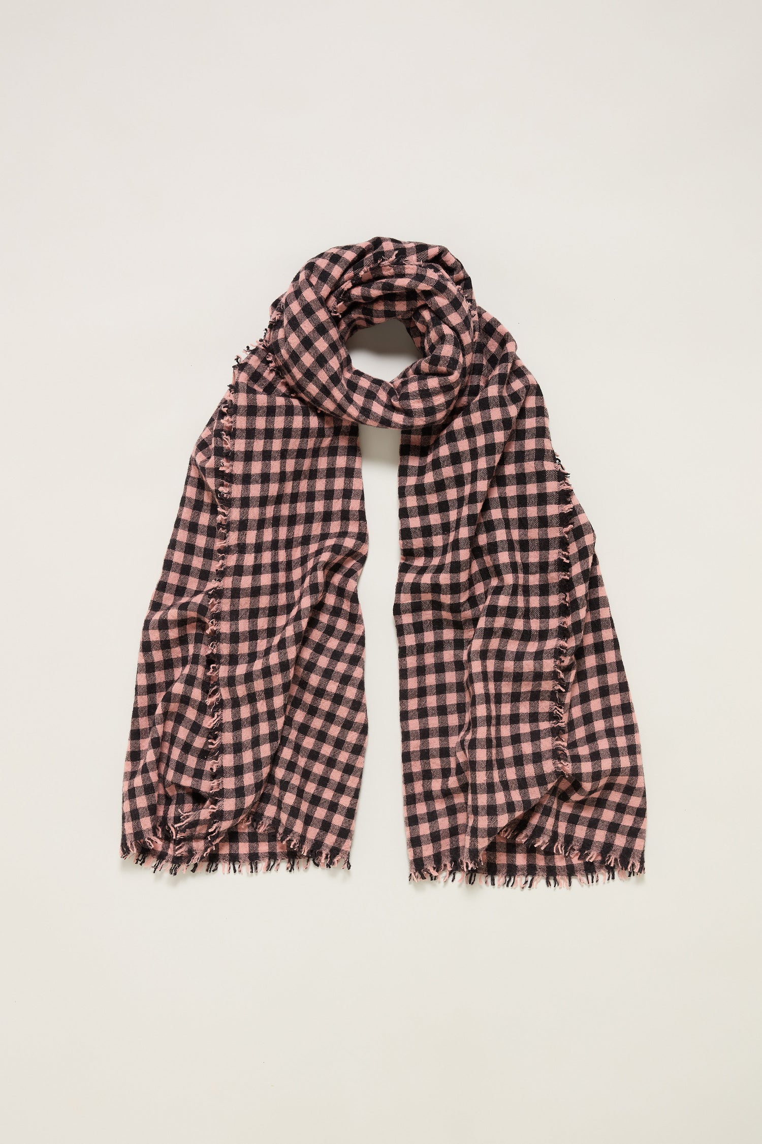 The Boiled Wool Gingham Check Scarf, in black and pink with frayed edges, is displayed flat on a white background, combining lightweight warmth with stylish design.