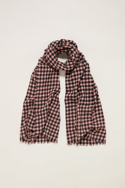 The Boiled Wool Gingham Check Scarf, in black and pink with frayed edges, is displayed flat on a white background, combining lightweight warmth with stylish design.