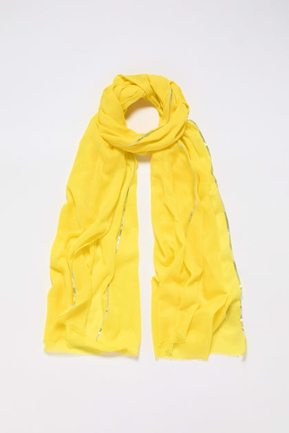 The Silver Edge Cotton Scarf, a bright yellow, lightweight cotton piece with subtle metallic accents, showcases its versatility and blends comfort with style when displayed flat on a plain background.