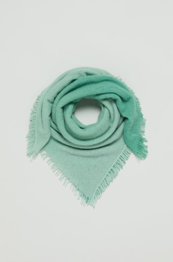 The Ombre Cashmere Square Scarf in light green is folded into a triangle and coiled neatly on a plain white background.