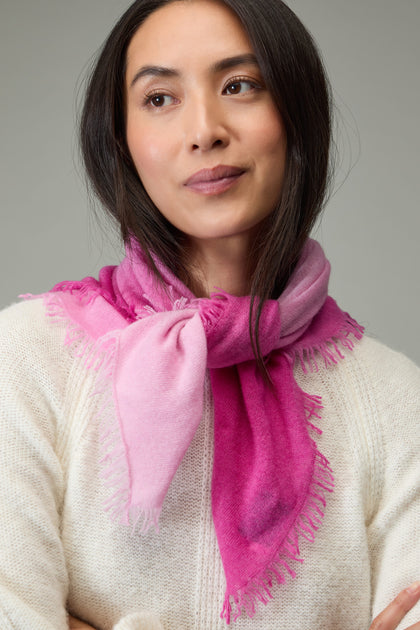 A woman in a white sweater wears the Ombre Cashmere Square Scarf, looking to the side with arms crossed against a plain background.
