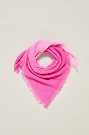 The Ombre Cashmere Square Scarf, in a pink fringed design, is folded into a triangle against a plain light background.