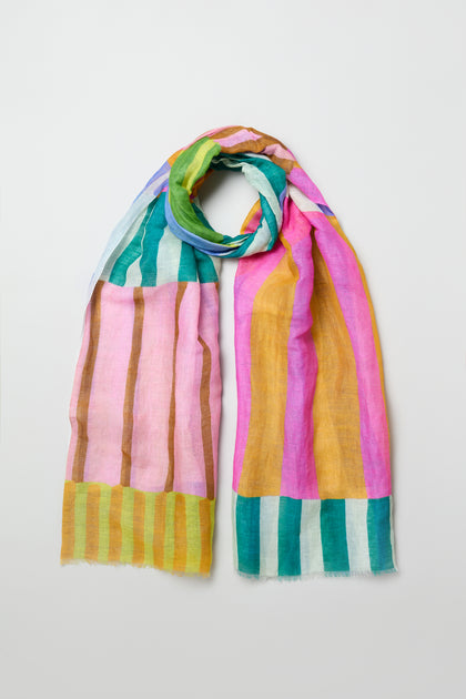 The Sunburst Block Print Linen Blend Scarf is a lightweight woven scarf featuring vertical and horizontal stripes in pink, yellow, green, blue, and brown tones, displayed flat on a plain light background.